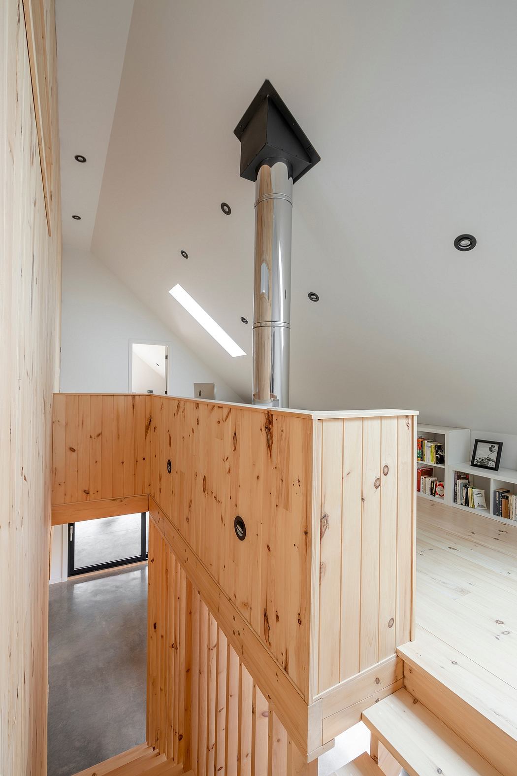 A modern, wooden staircase with a sleek metal railing, leading to a loft-like space.