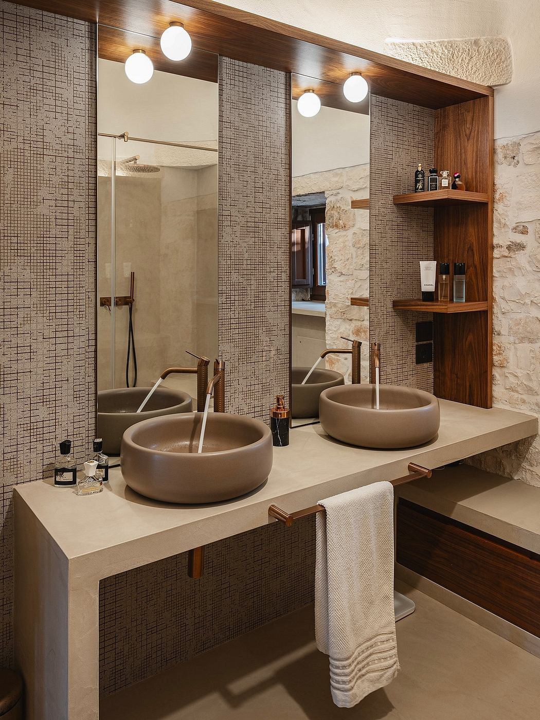Elegant bathroom with mosaic tiled walls, wooden shelves, and circular vessel sinks.