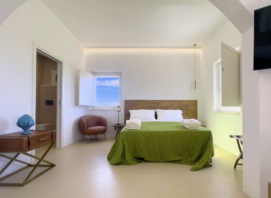 Spacious bedroom with minimalist design, wooden headboard, and green bedding.