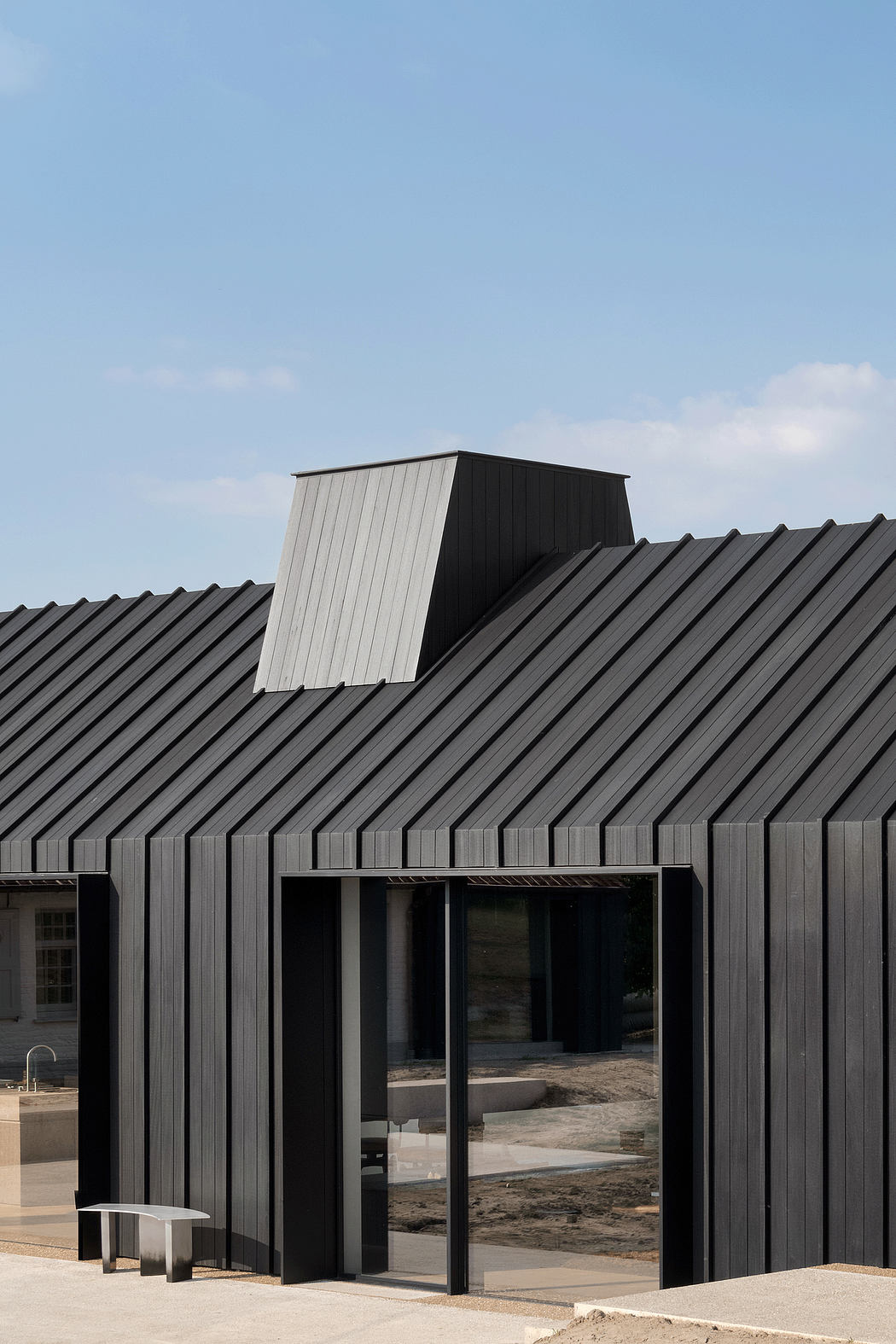 Modern black metal-clad building with angled roofline and large glass windows.