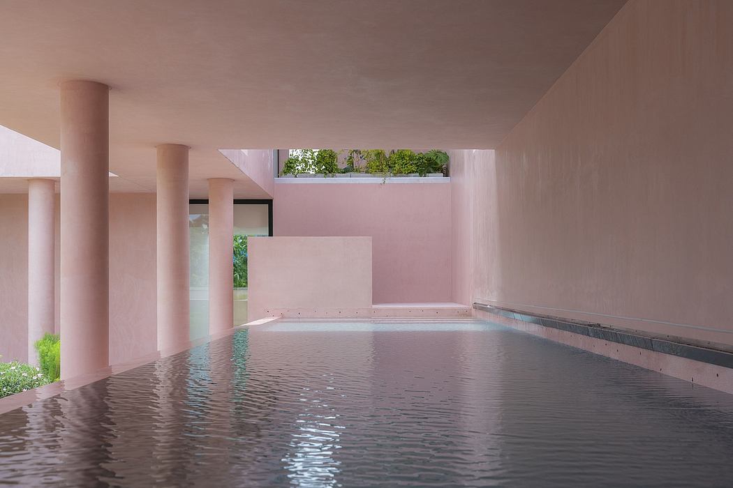 Pink-hued interior with a minimalist pool and vegetation visible through a large window.