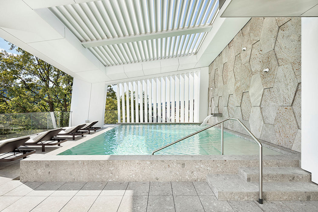 Elegant modern pool area with sleek white ceiling beams, stone walls, and lounge chairs.