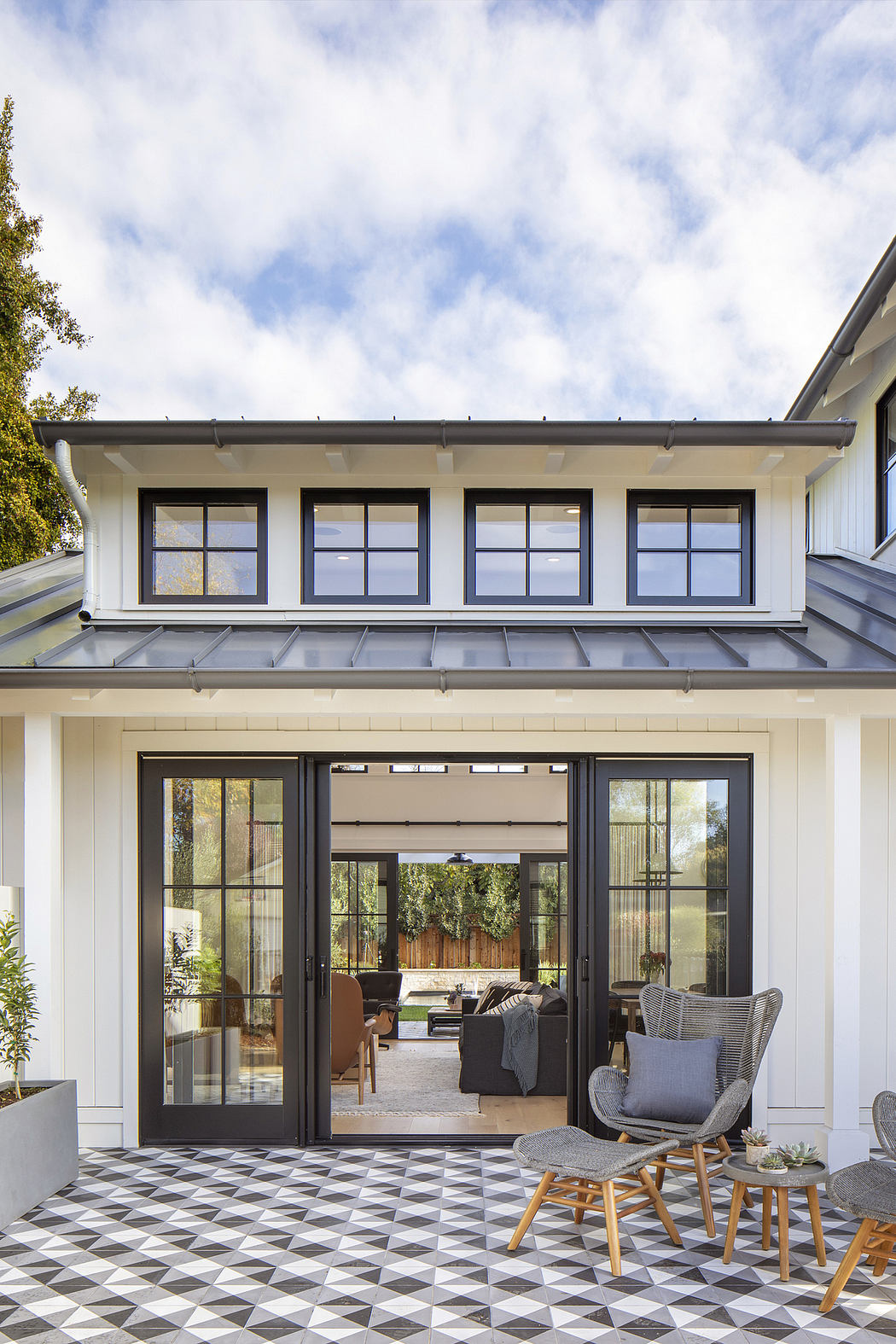 Stylish patio with monochrome tiled floor, glass doors, and contemporary furnishings.