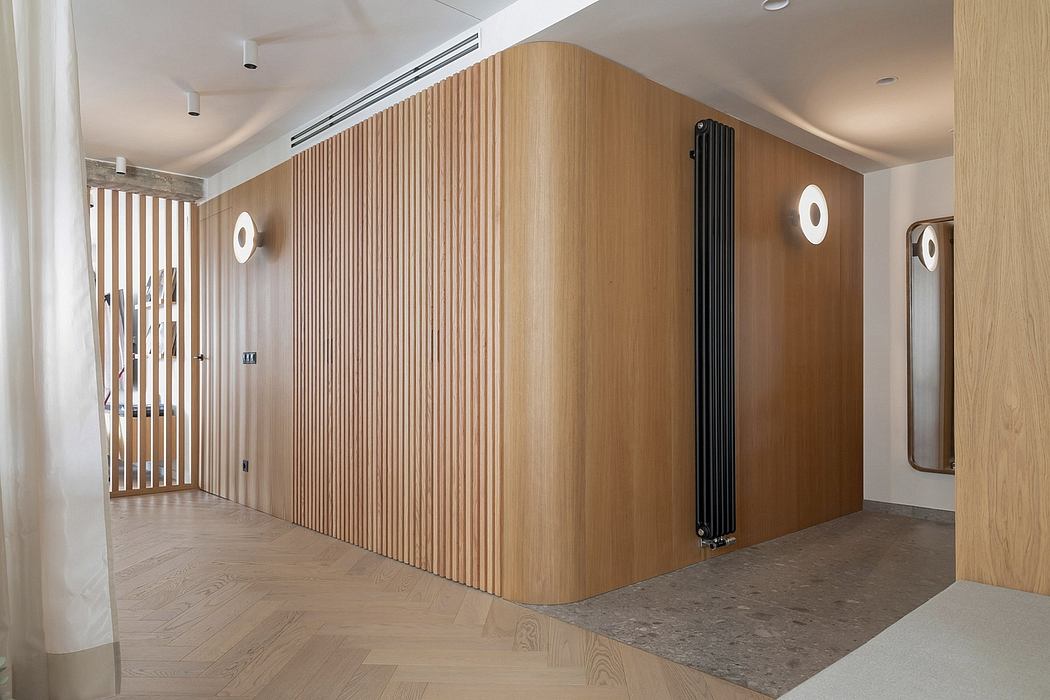 A modern hallway with wood paneled walls, recessed lighting, and a sleek black radiator.