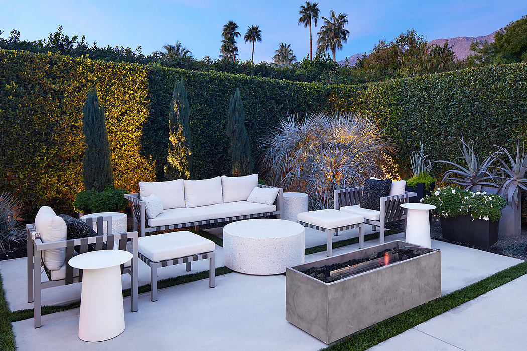 A modern outdoor living space with minimalist furniture, fire pit, and lush landscaping.