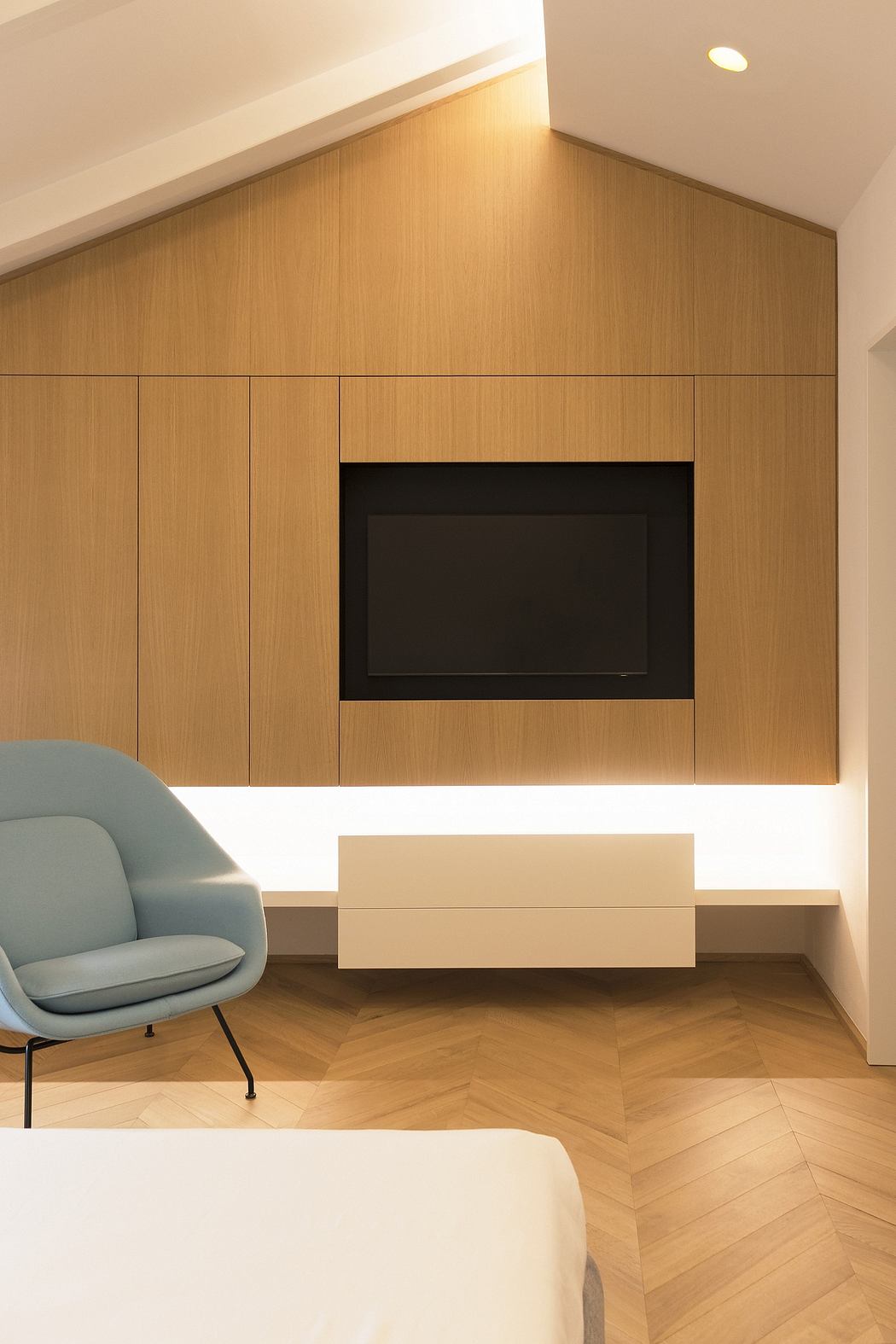 Minimal, modern interior design with wooden panels, built-in TV, and armchair.