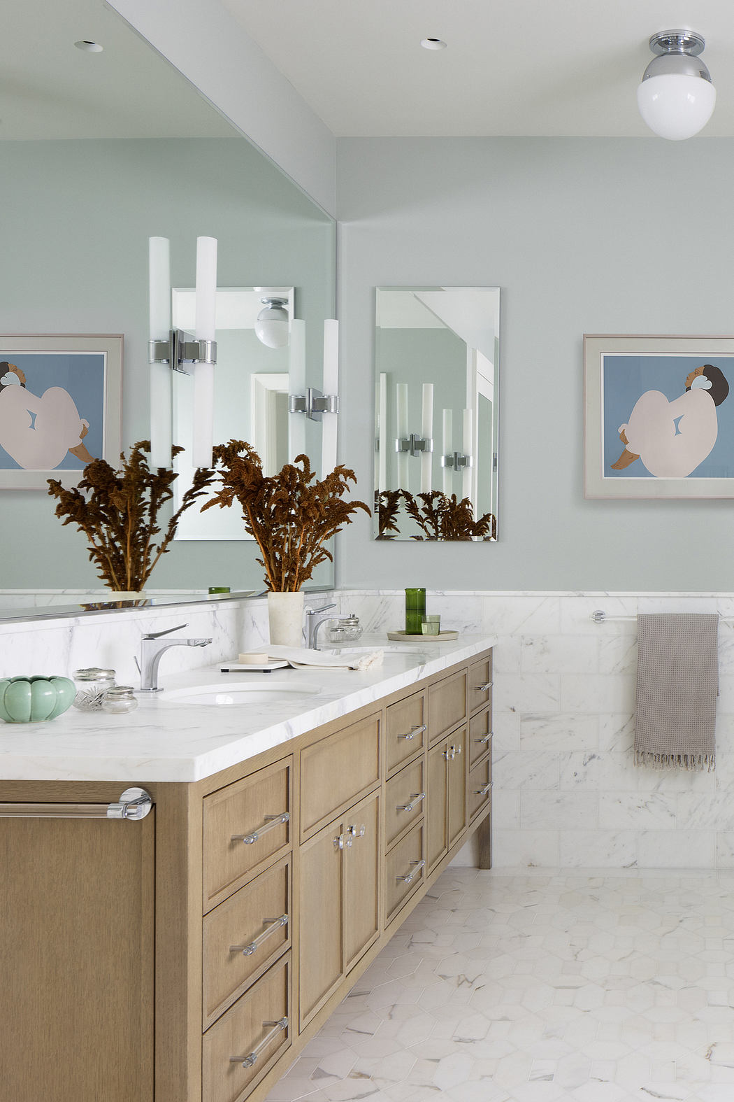 Bright, minimalist bathroom with marble countertops, built-in drawers, and modern light fixtures.
