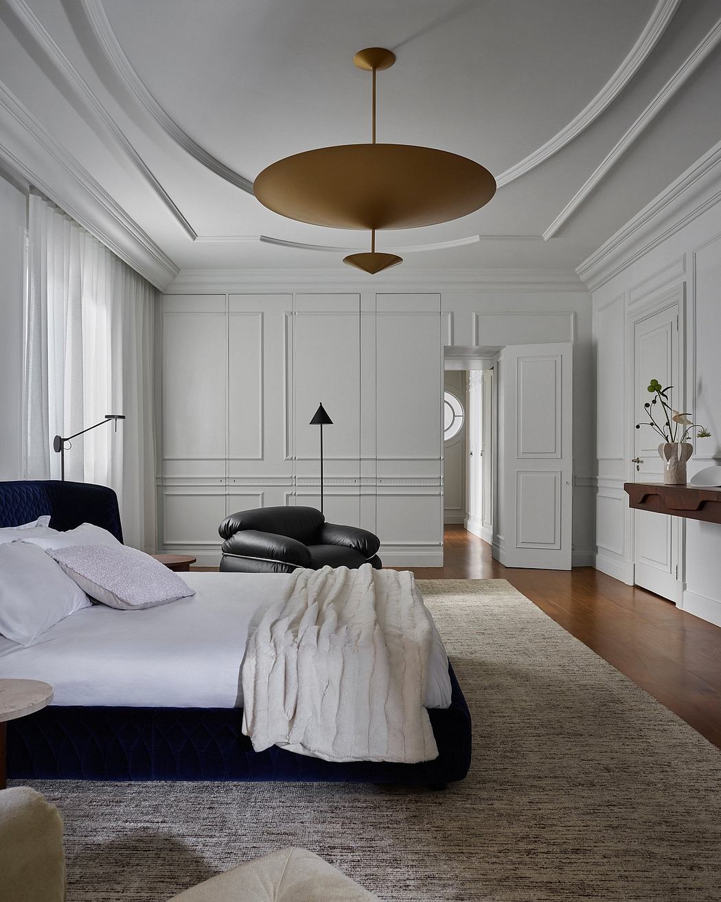 Elegant bedroom with layered lighting, built-in cabinetry, and a striking suspended light fixture.