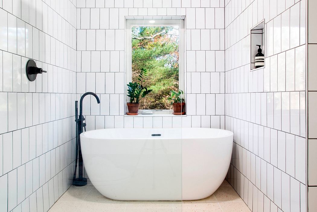 Modern bathroom design with freestanding tub, tiles, and views of the outdoors.