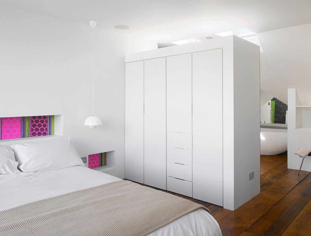 A minimalist bedroom with a large white wardrobe, wooden floor, and modern lighting.