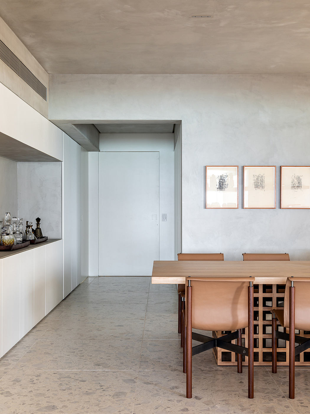 Minimalist dining room with concrete walls, sleek wooden table, and abstract art.