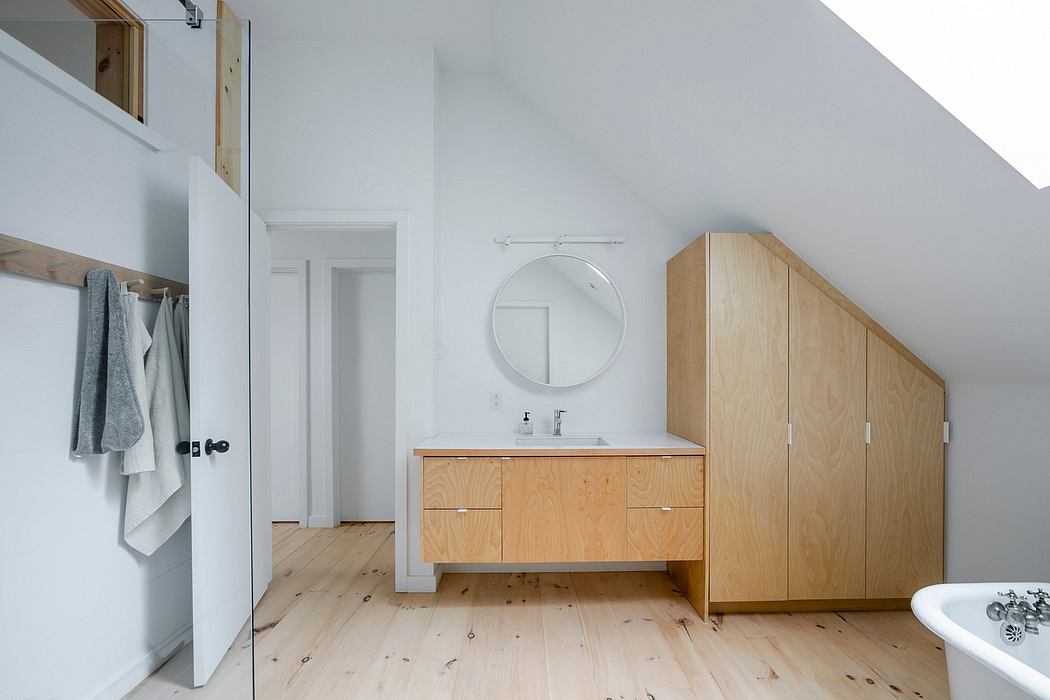Minimalist bathroom design featuring wooden vanity, circular mirror, and modern fixtures.