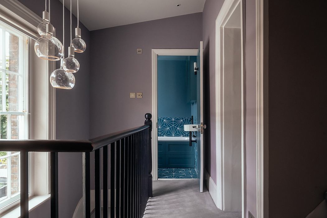 Sleek contemporary hallway with bold geometric patterns, pendant lights, and wooden railing.