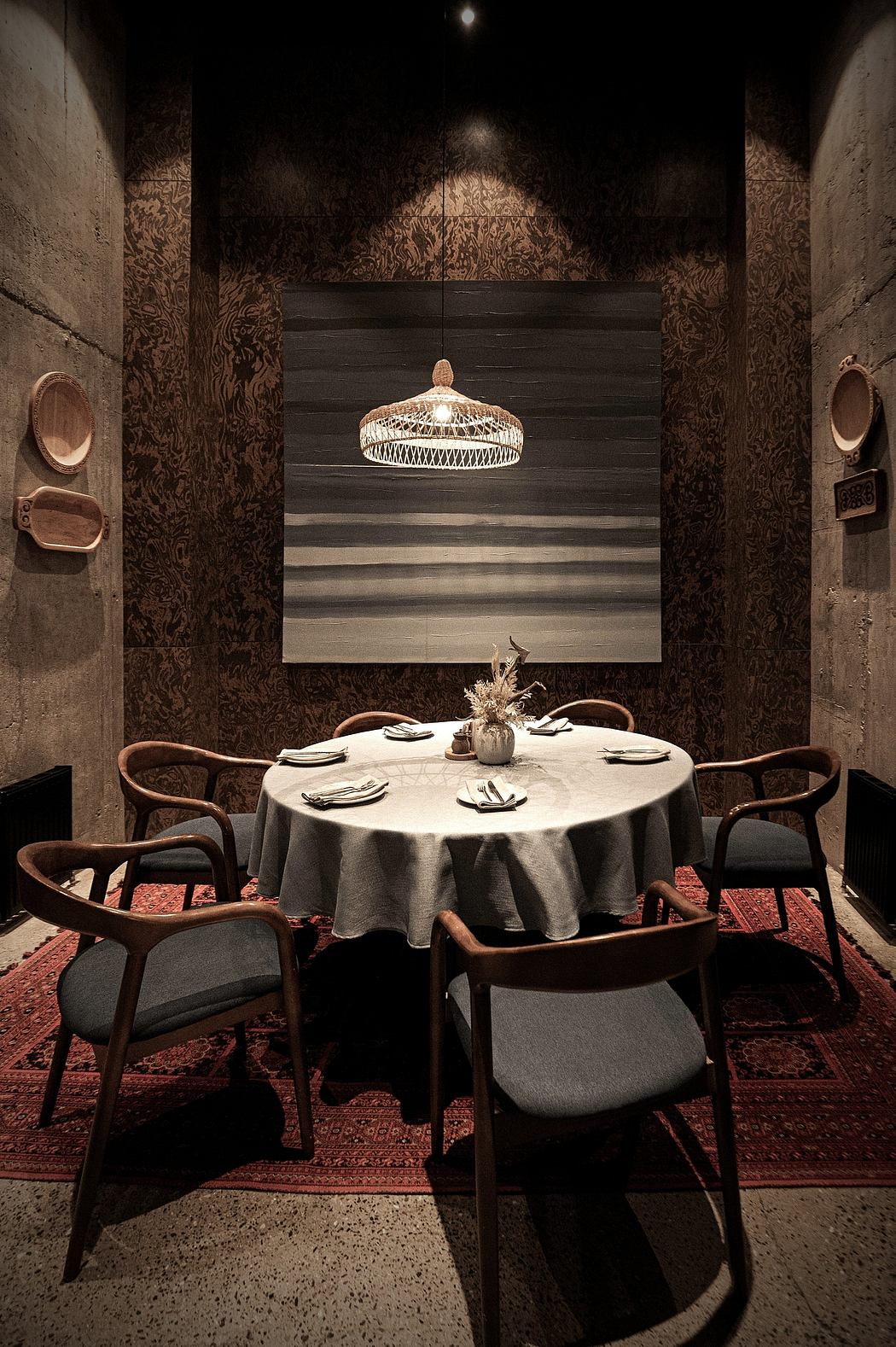 Moody dining room with ornate light fixture, patterned walls, and round table set.