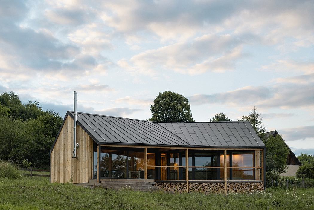 A contemporary wooden cabin with a metal roof, surrounded by lush greenery and a cloudscape.
