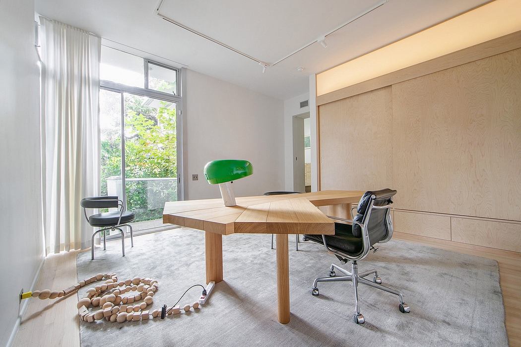 Minimalist home office with wooden furniture, large window, and artistic elements.