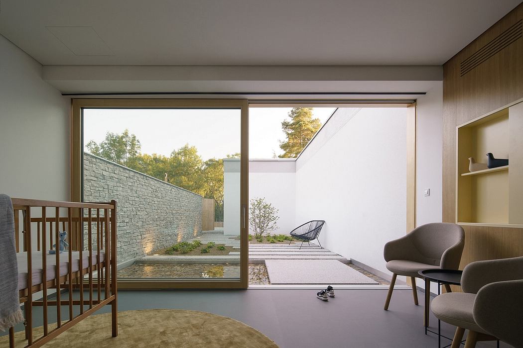 Modern home interior with large windows, wooden accents, and minimalist furnishings overlooking a serene outdoor garden.