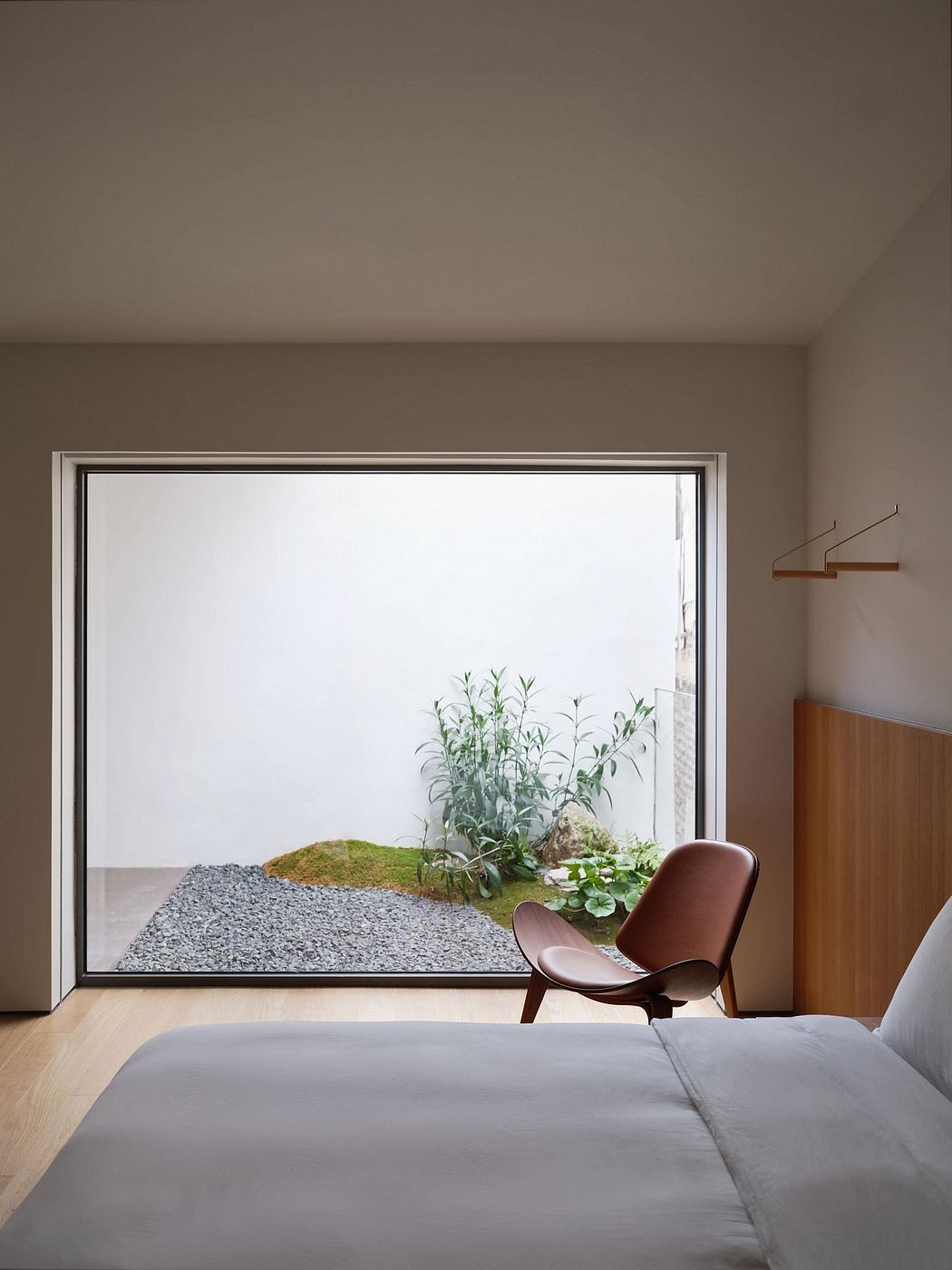 Minimalist bedroom design featuring a large window framing a serene landscape garden.