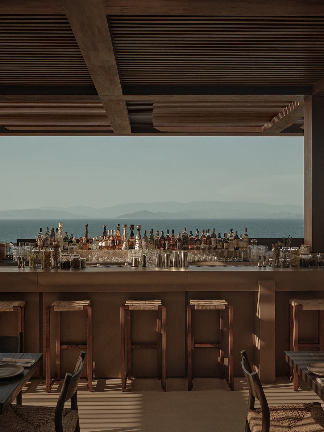 Rustic wood-lined bar with an impressive array of liquor bottles and glasses overlooking a scenic vista.