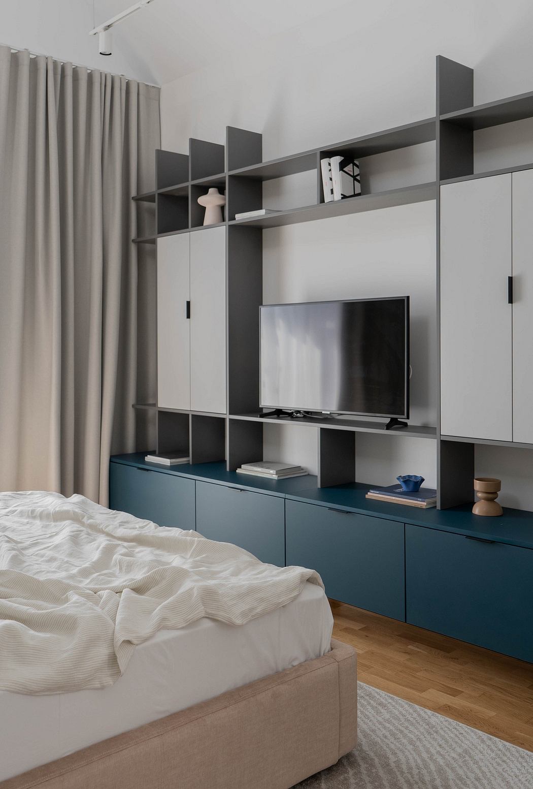 Minimalist bedroom with custom wall-mounted entertainment unit and built-in storage.