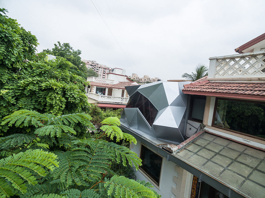 The image shows a geometrically designed rooftop structure amidst lush greenery and buildings.