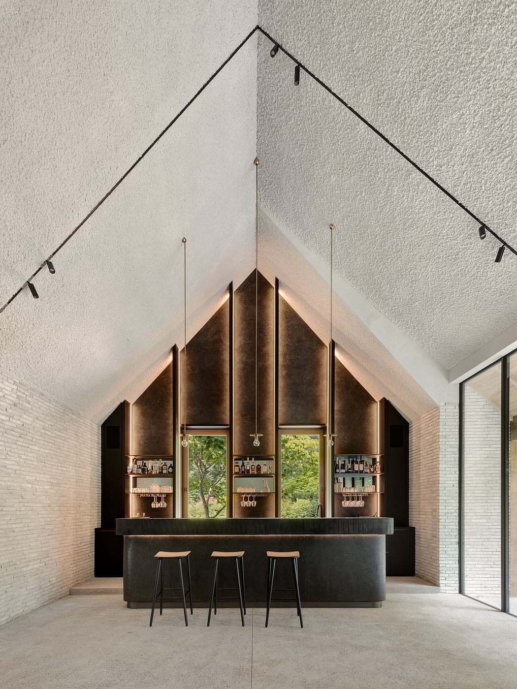 Striking angular design with reflective surfaces and dramatic lighting, creating a modern bar space.