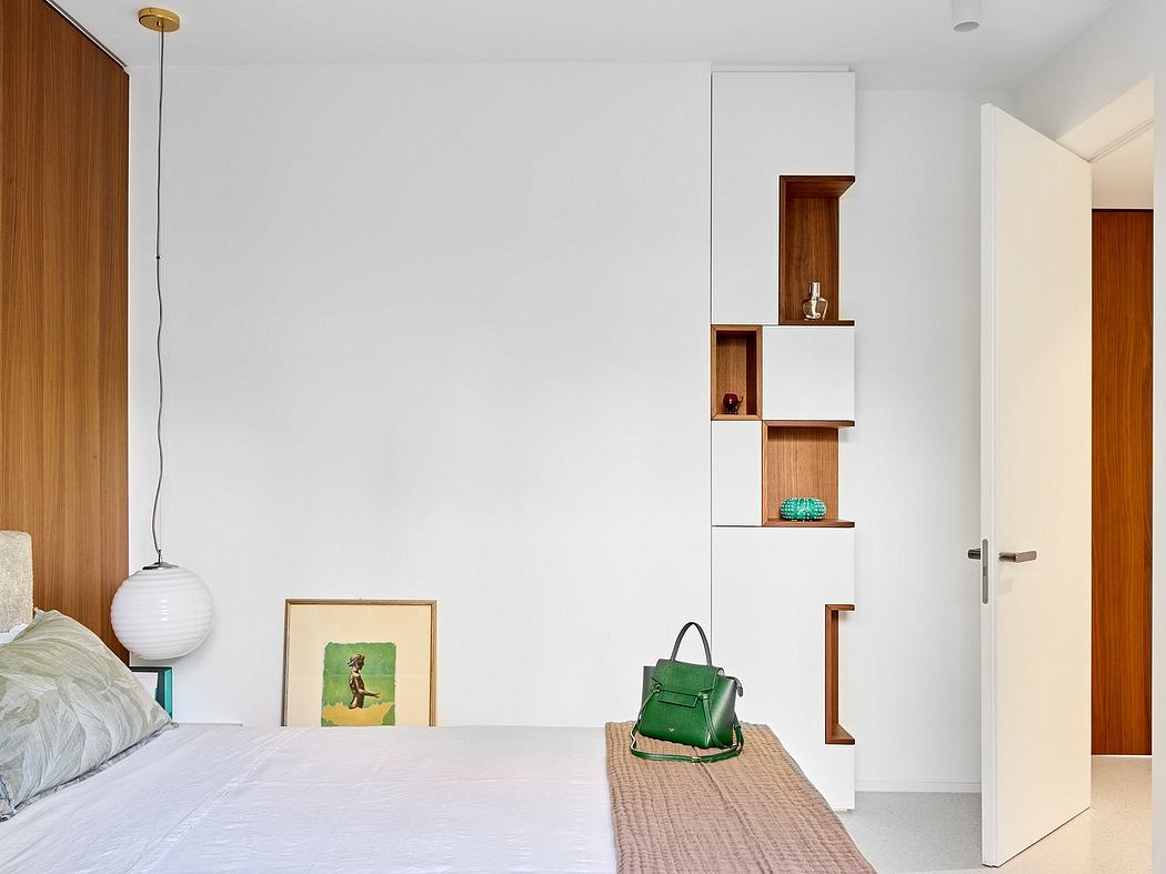 A minimalist bedroom with wooden accents, built-in shelving, and a modern white pendant lamp.
