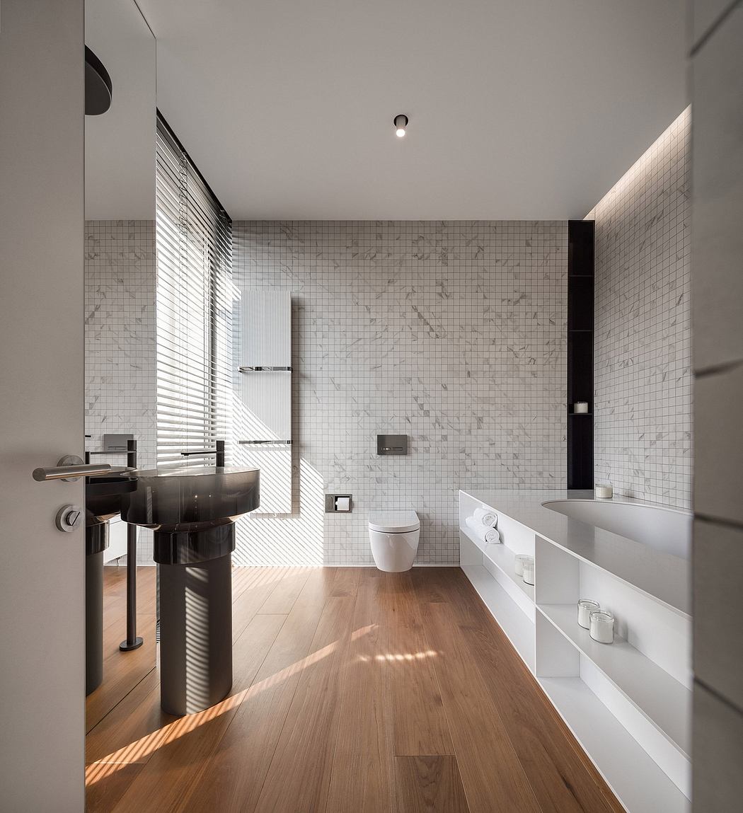 Modern bathroom with marble tile walls, wood floor, and minimalist vanity.