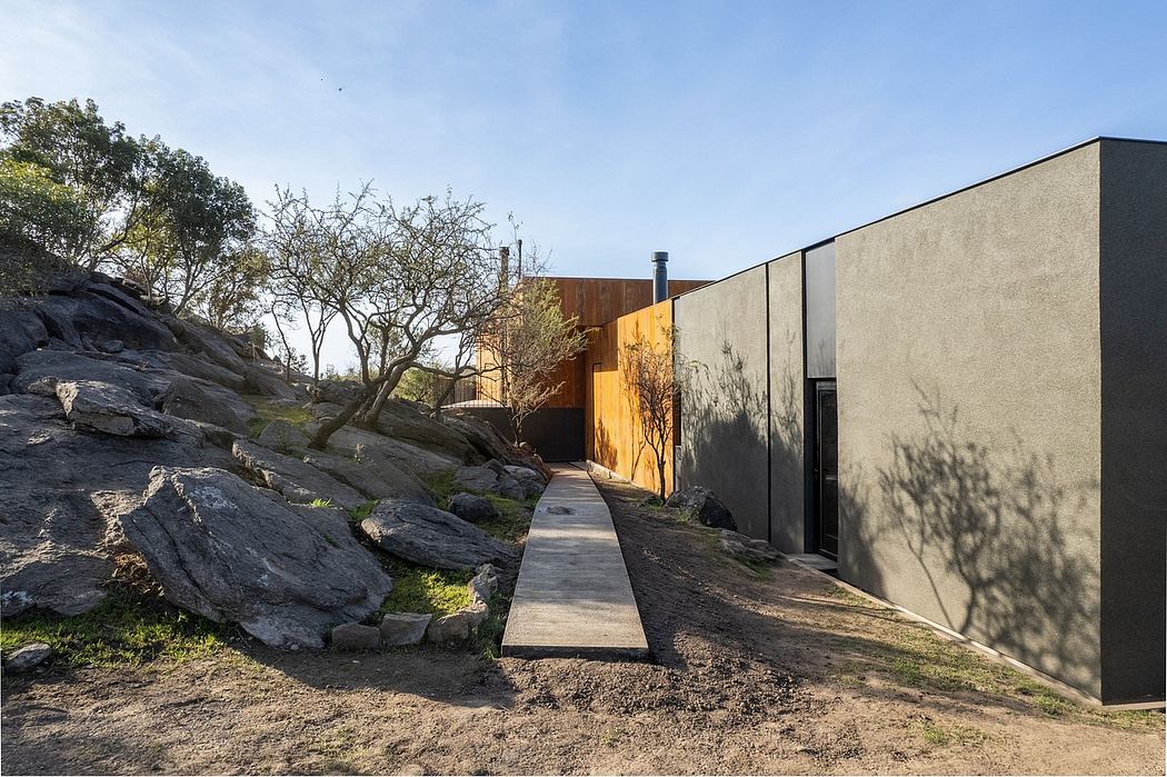 A modern, angular building nestled among rock formations and natural vegetation.