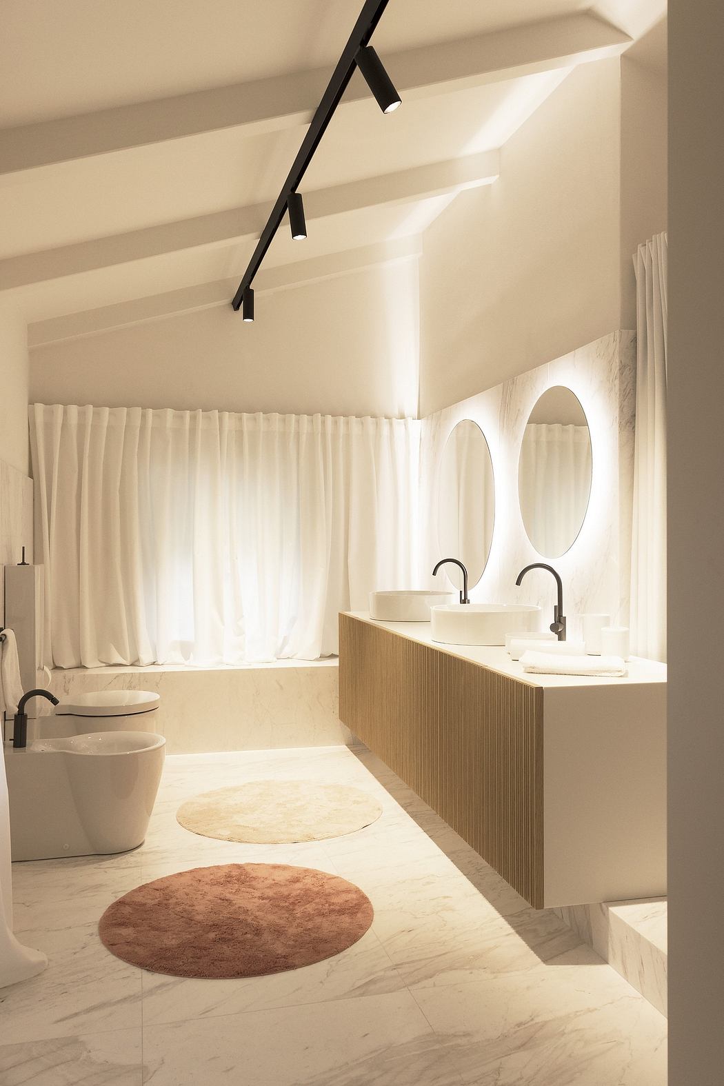 Inviting contemporary bathroom with sleek vanity, round mirrors, and warm lighting.