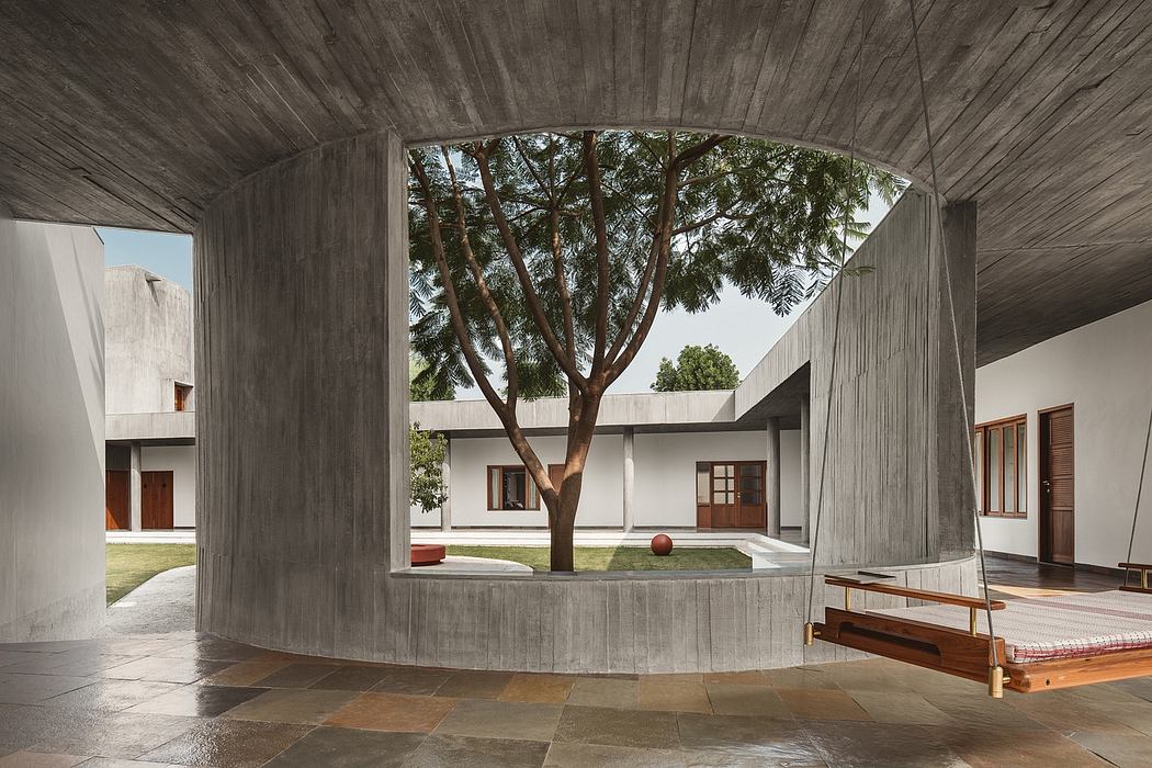 A concrete structure with arched entrance framing a lush tree in a courtyard.