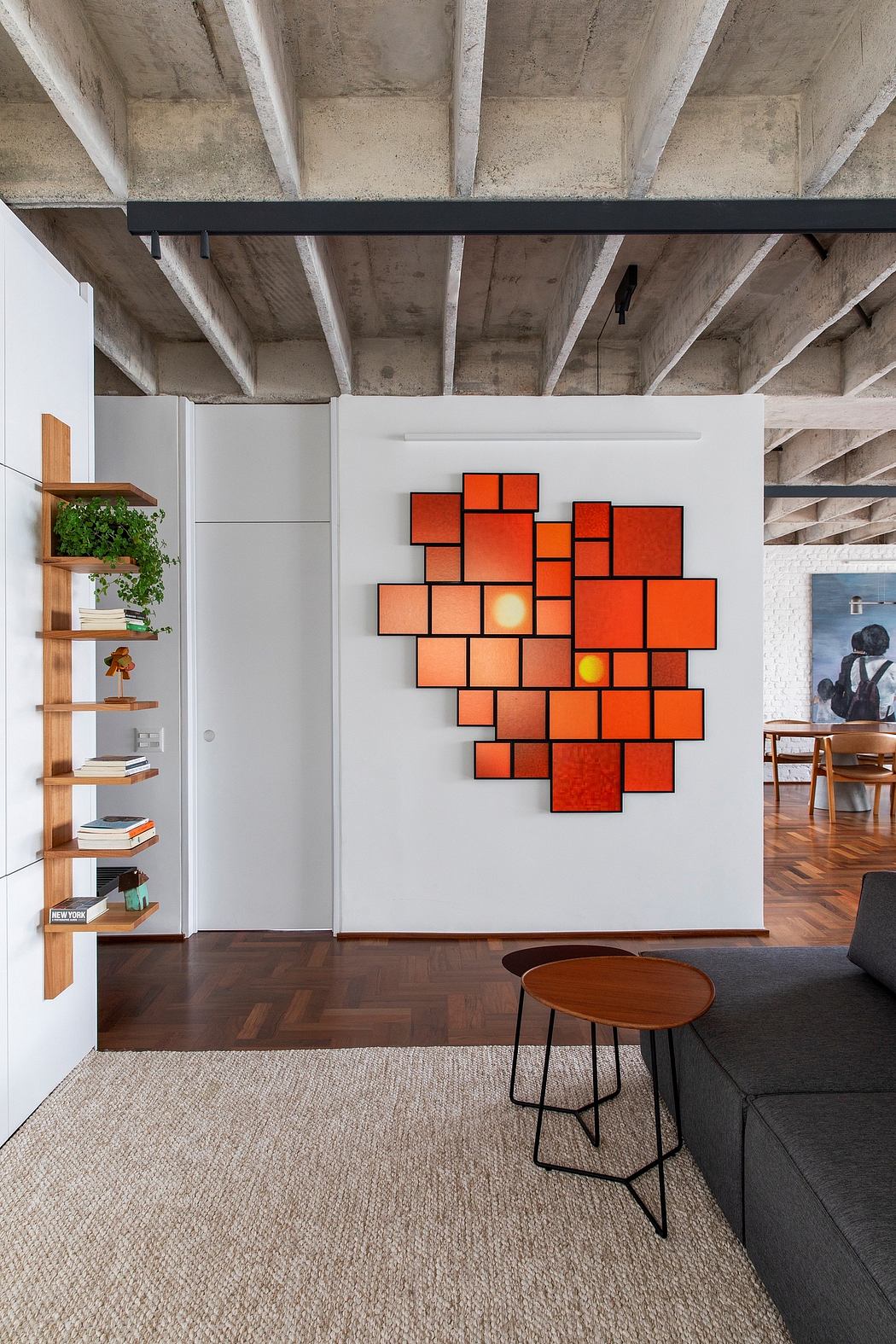 Striking concrete ceiling beams, modular orange art piece, and minimalist furniture.