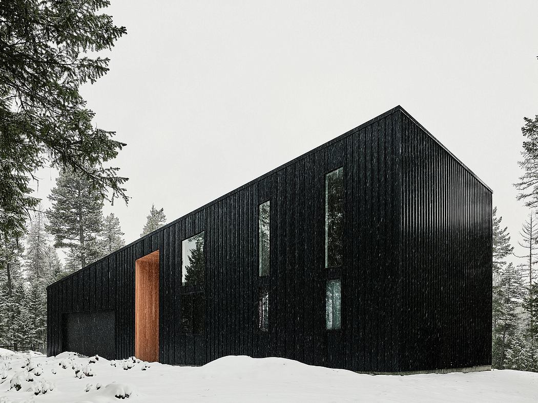 A modern black wooden cabin nestled in a snowy forest, featuring a warm wooden entrance.