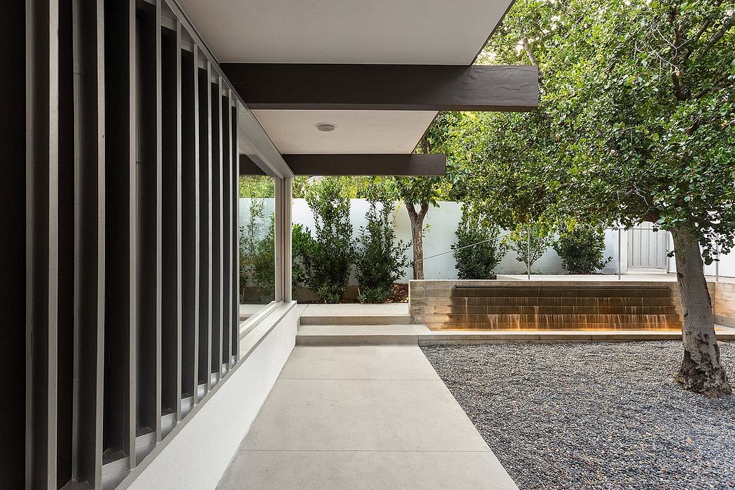 A modern architectural exterior with a concrete pathway, glass walls, and greenery.