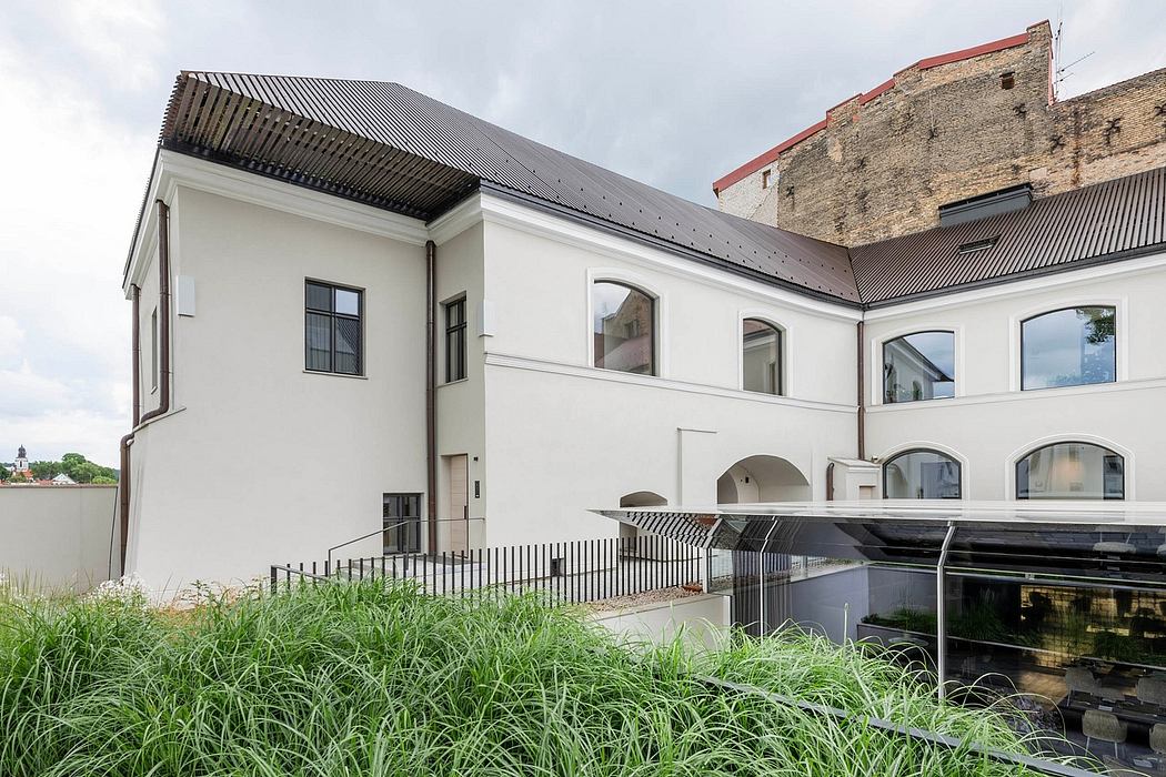 A contemporary addition to a historic structure, featuring arched windows and a sleek metal roof.