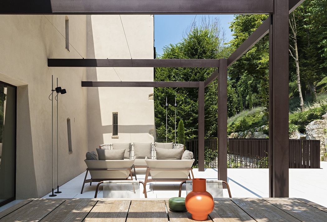 Sleek modern architecture with a covered patio, outdoor seating, and lush greenery.