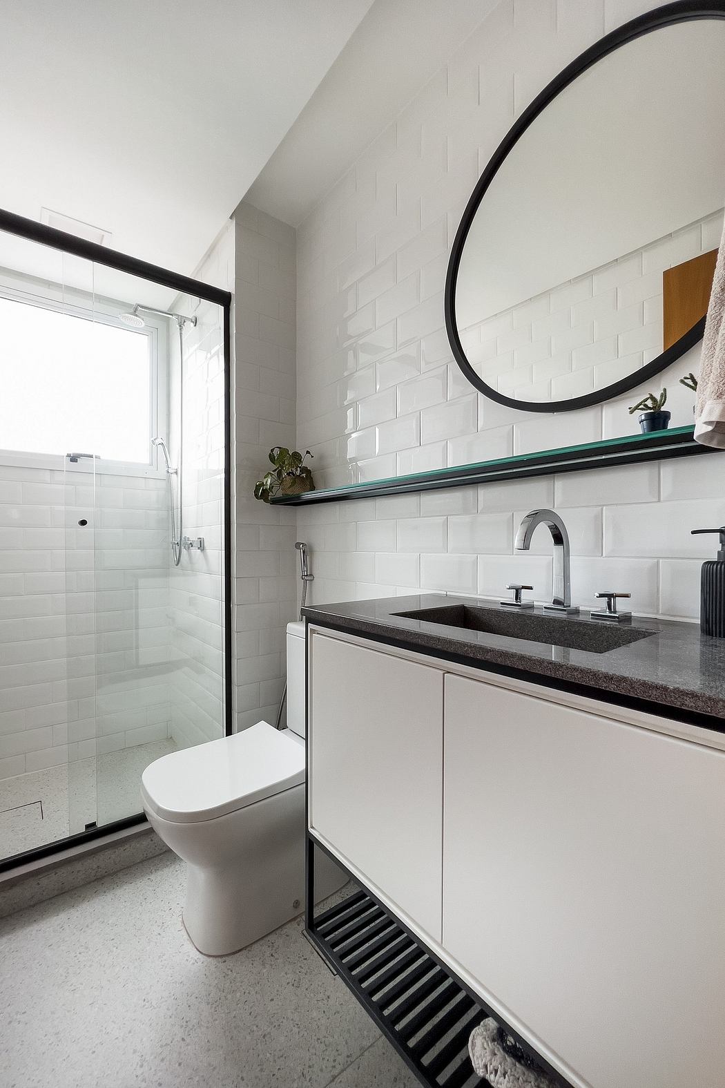 Minimalist bathroom with white tiles, black accents, and a floating vanity with a deep sink.
