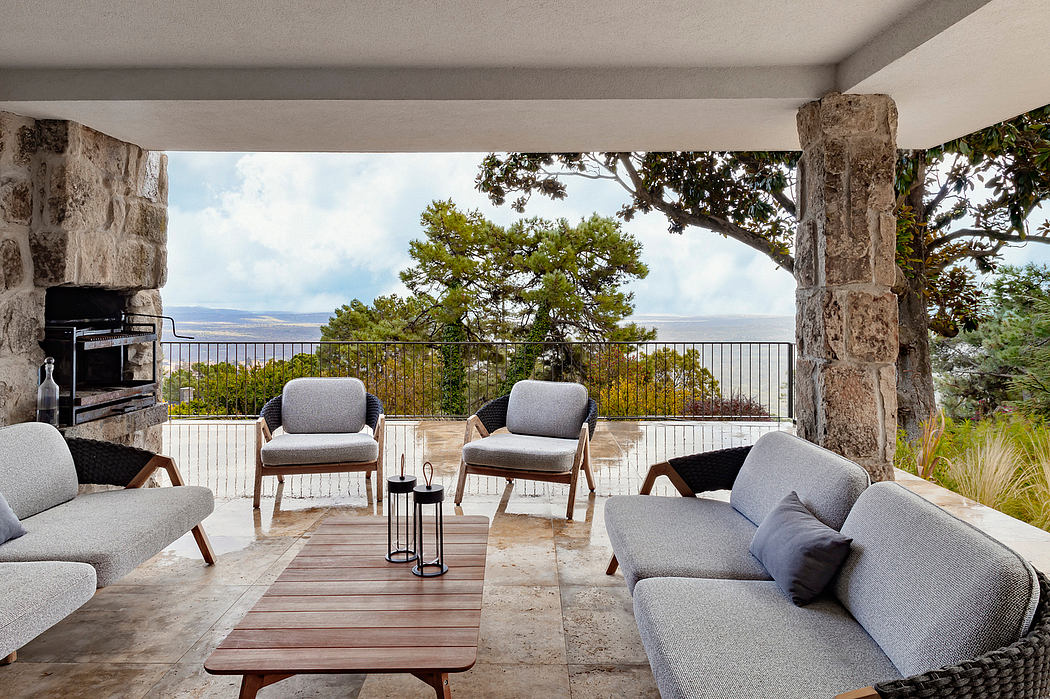 Spacious covered outdoor living area with stone columns, wood furniture, and scenic views.