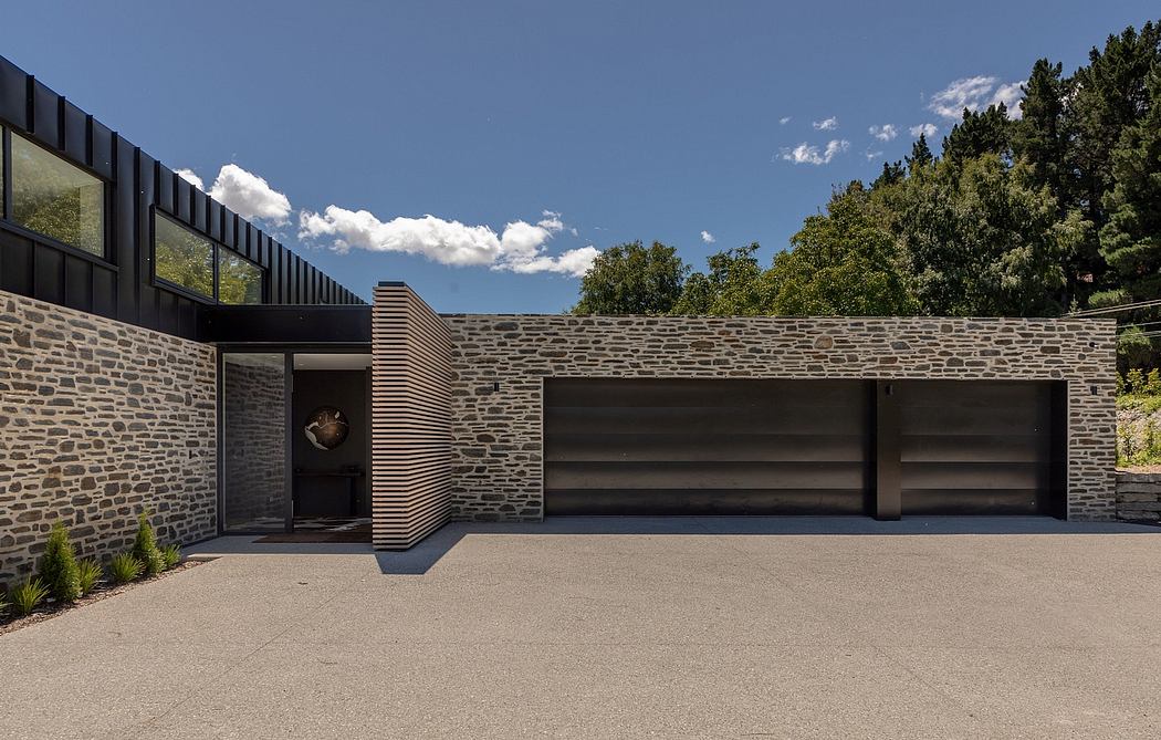 Modern stone and wood exterior with sleek garage doors and sheltered entrance.