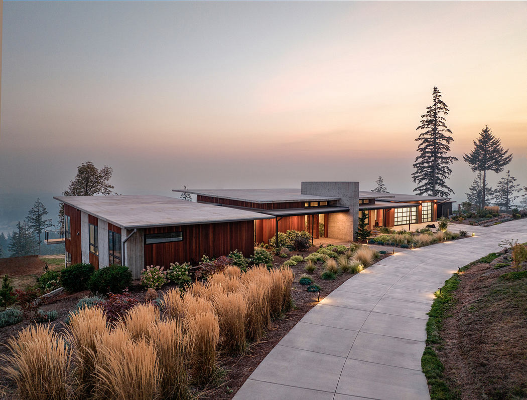 A modern rural home with wood siding, concrete walkway, and landscaped surroundings.