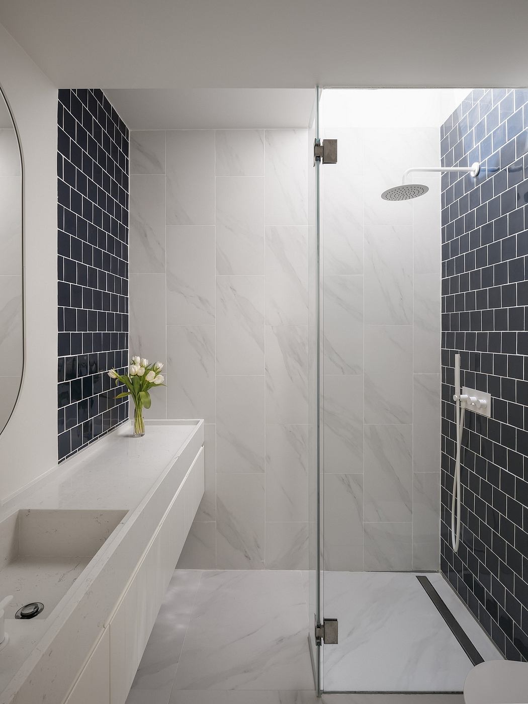 Sleek, minimalist bathroom with black subway tile accents and a glass shower enclosure.