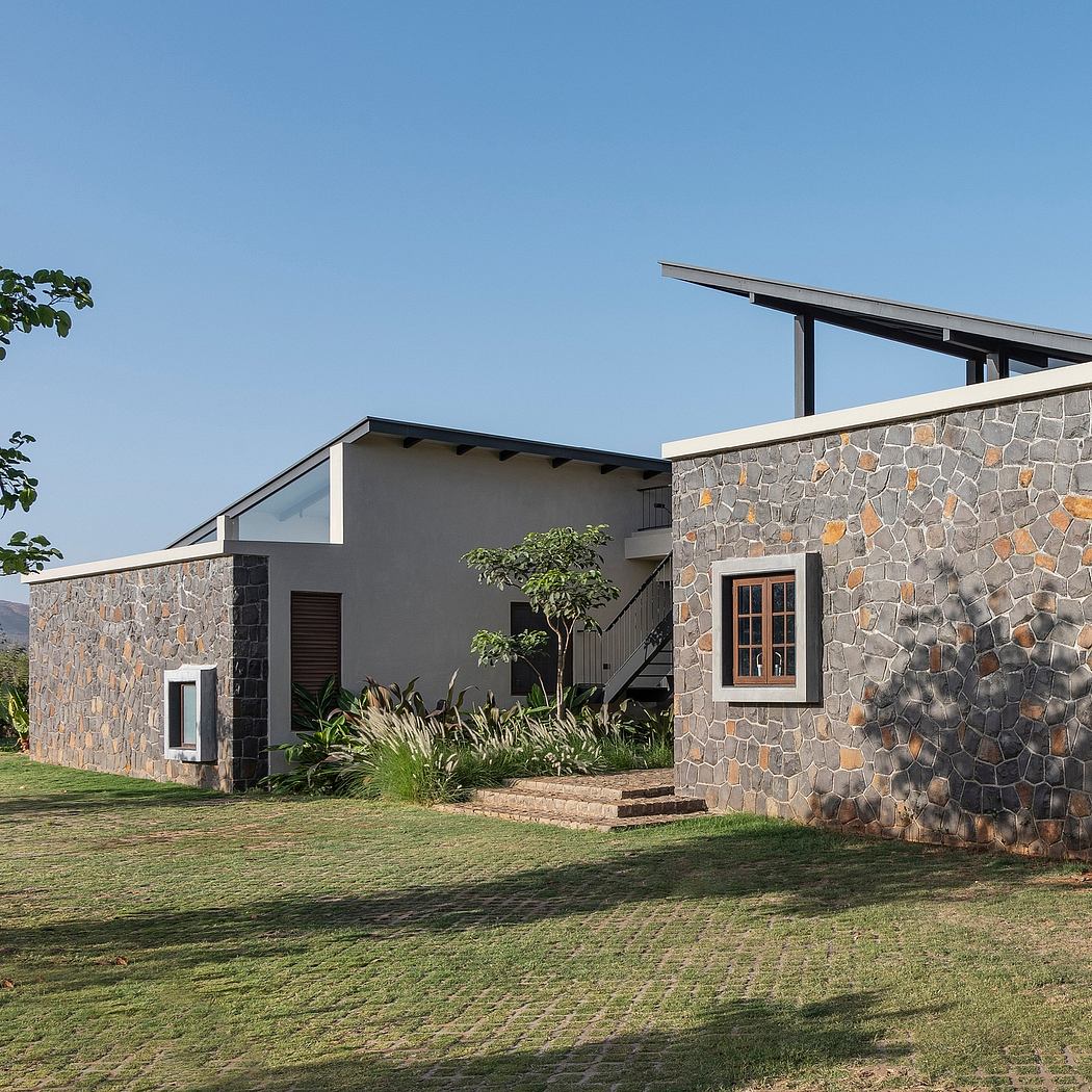 A modern stone-clad residence with a pitched roof and a lush, landscaped yard.