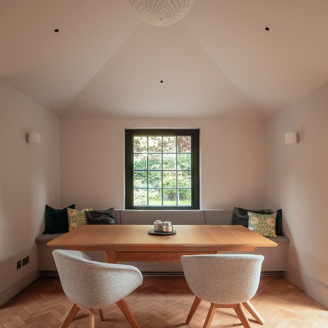 Cozy interior with wooden table, upholstered bench seating, and large window framing the garden.