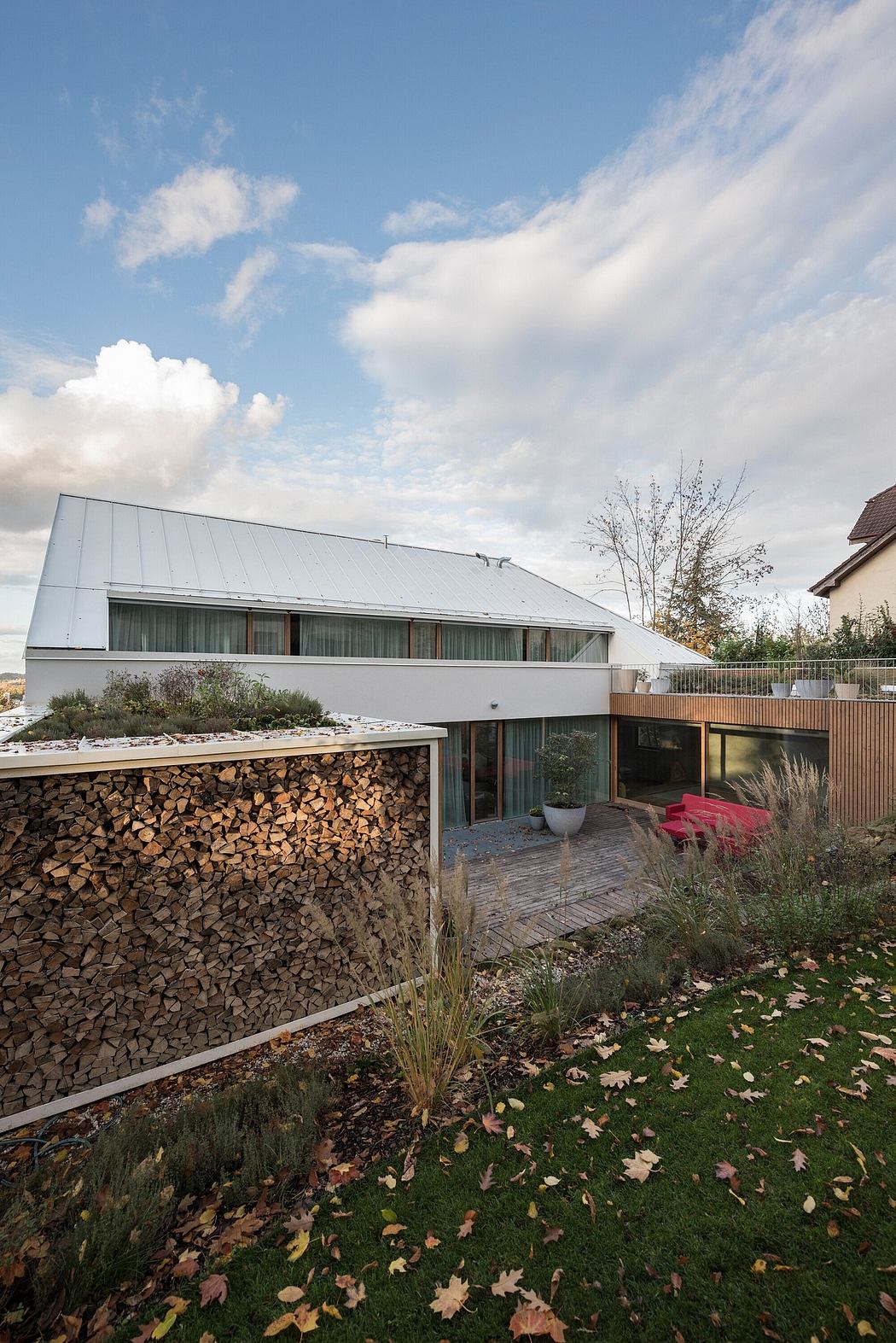 Contemporary house with wood paneling, large windows, and a storage area for firewood.