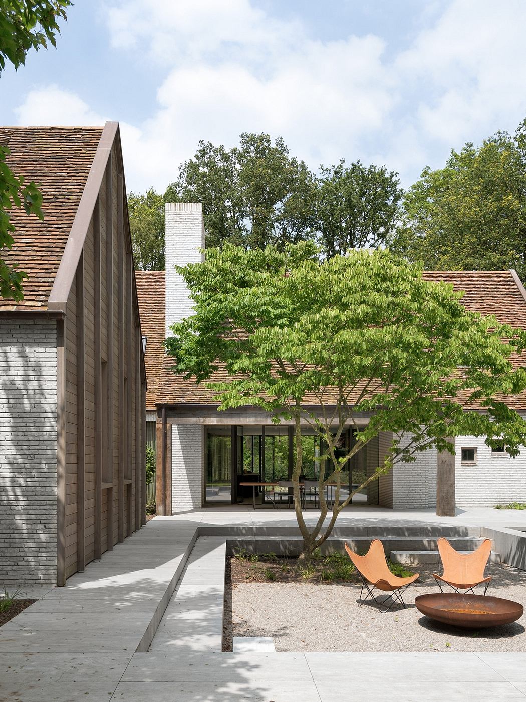 A modern home with a sophisticated architectural design, featuring a spacious outdoor patio and lush greenery.