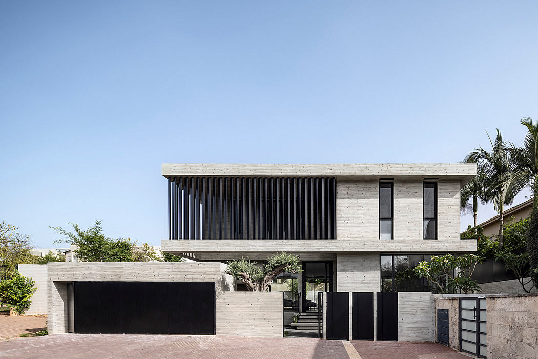 A modern, concrete house with a sleek, geometric facade and large windows overlooking greenery.