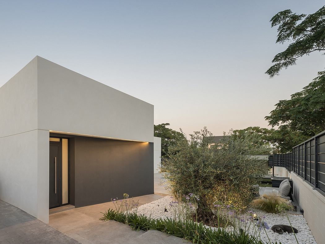 A modern, single-story structure with clean lines, surrounded by lush vegetation and a minimalist landscape design.