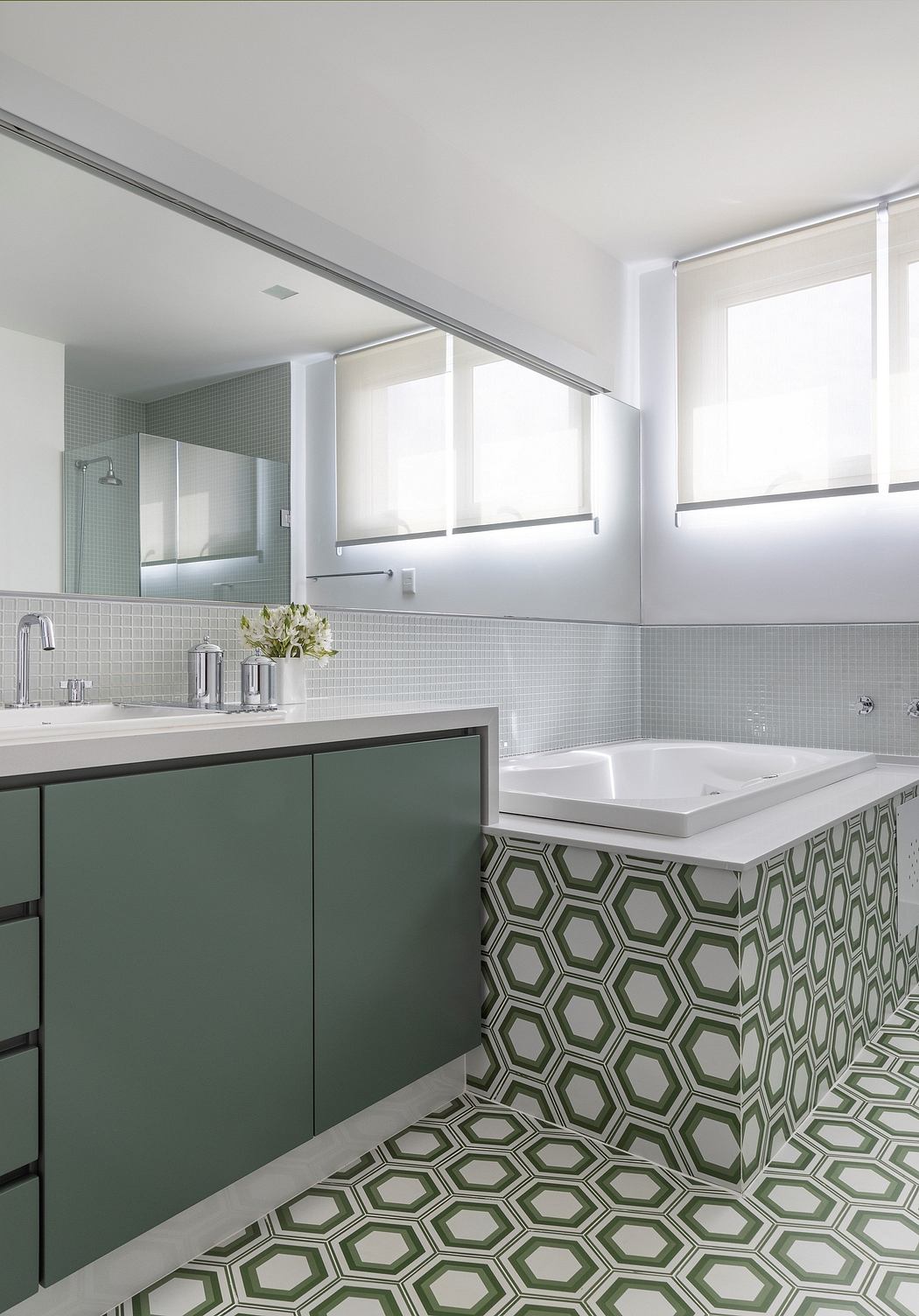 Minimalist bathroom design with sleek green cabinetry, mosaic tile floor, and bright windows.