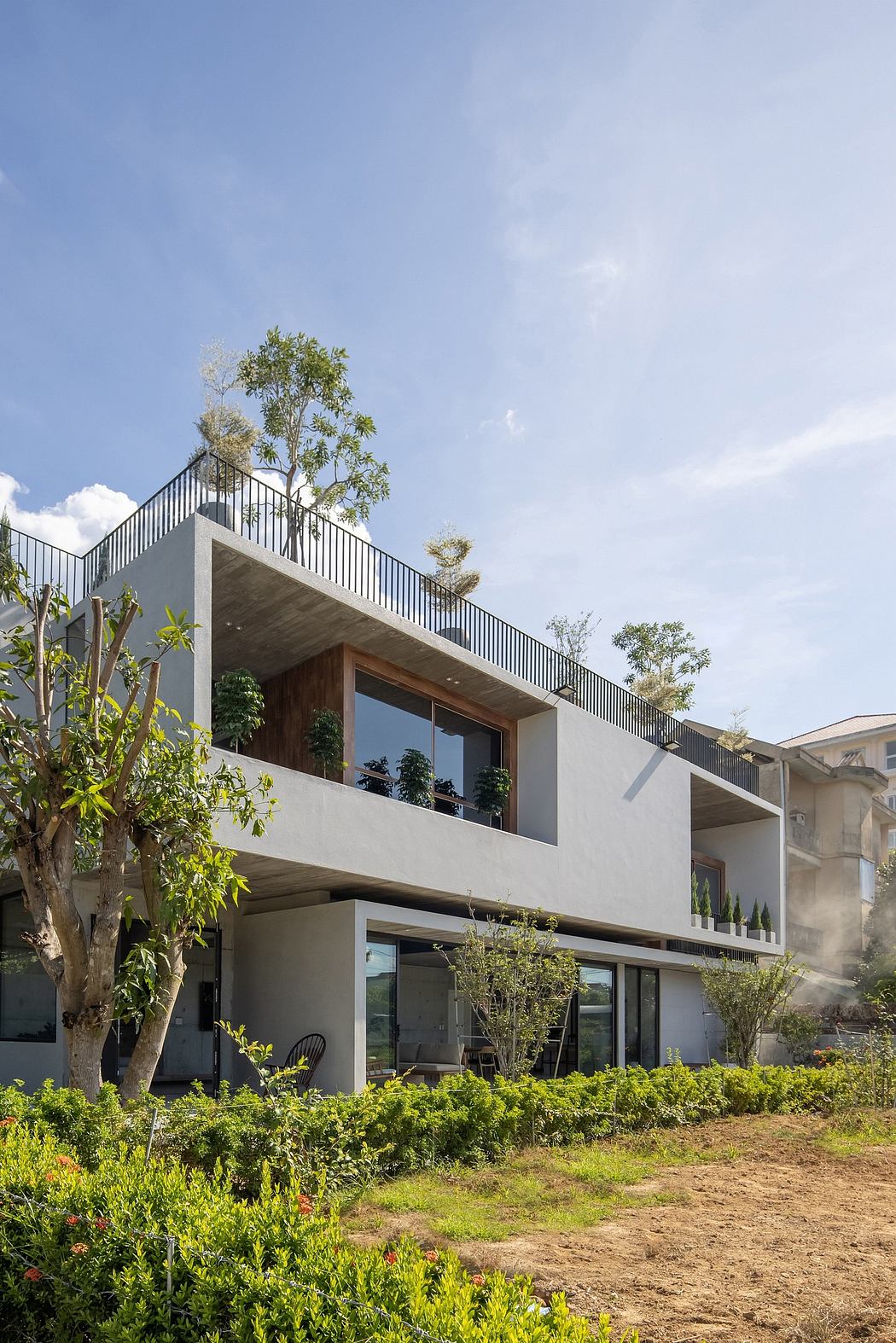 Contemporary two-story building with balconies, sleek metal railings, and lush greenery.
