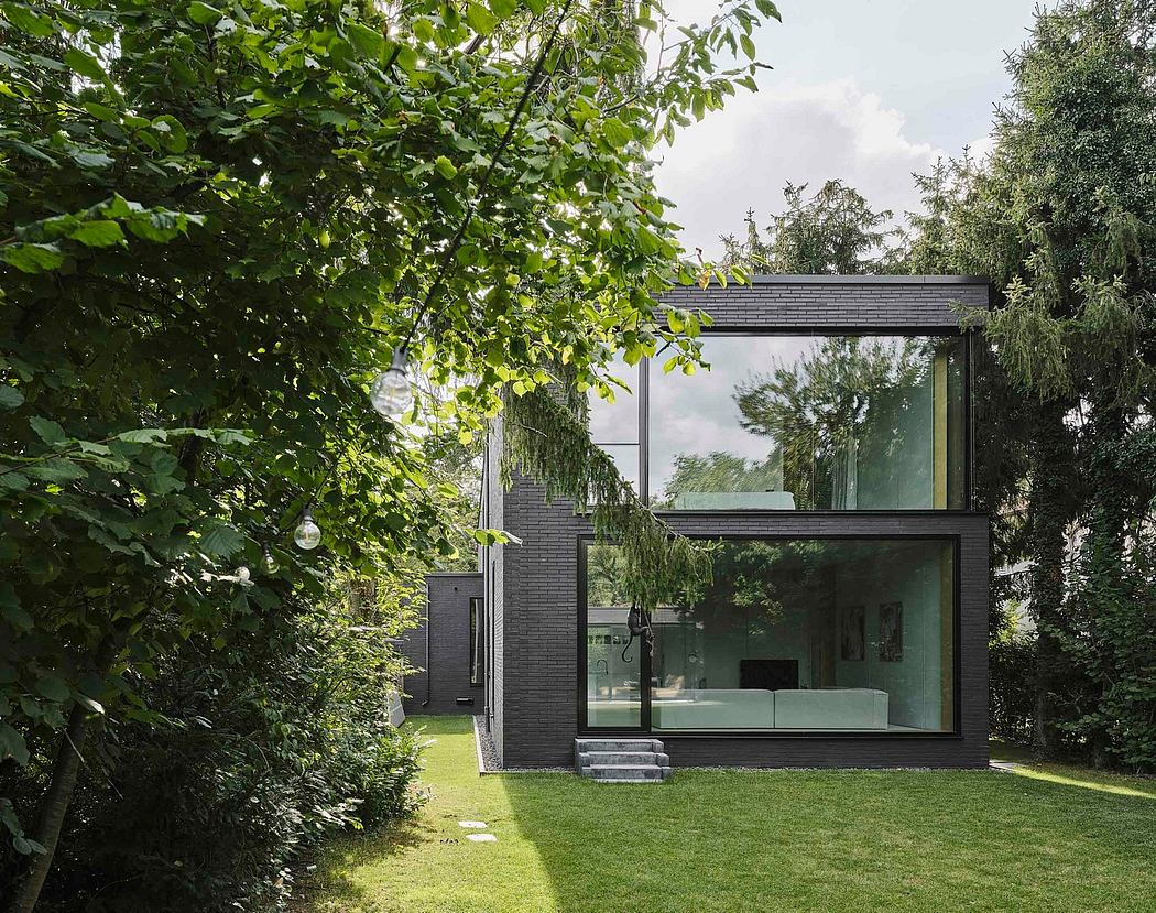 A modern glass and brick structure surrounded by lush greenery, with a minimalist design.